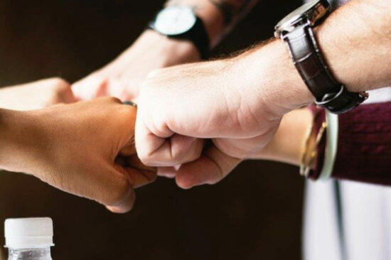 header - Equipe unie qui se retrouvent au centre pour un fist bump