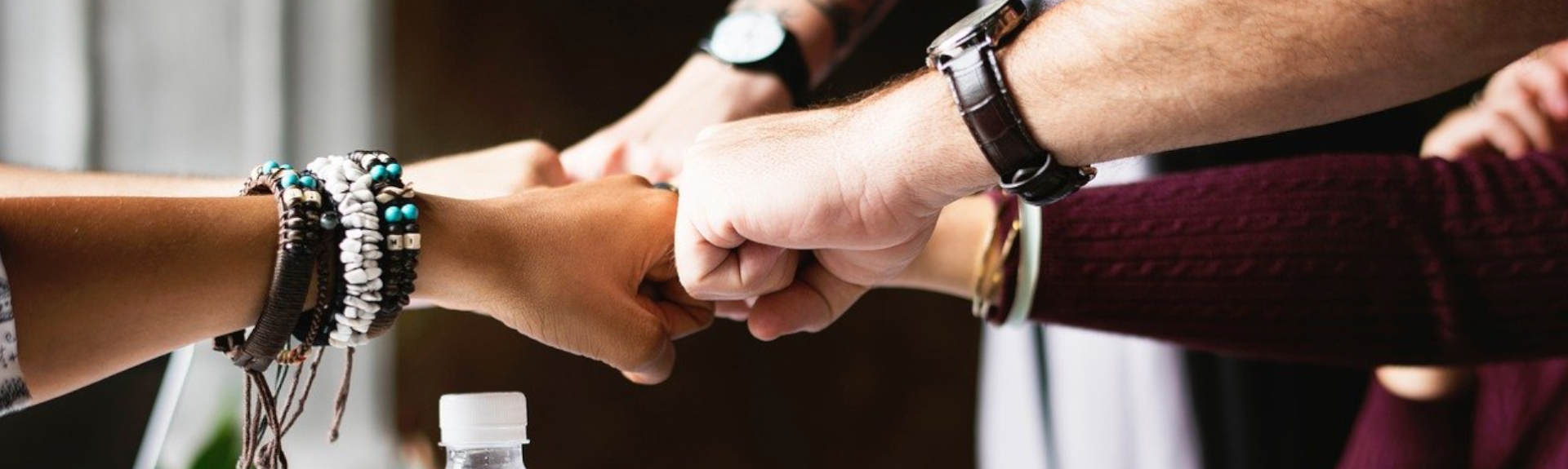 header - Equipe unie qui se retrouvent au centre pour un fist bump